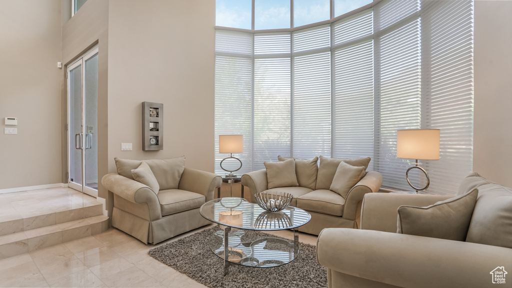 Living area featuring a towering ceiling and light marble finish flooring