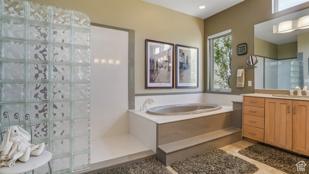 Bathroom featuring a garden tub, vanity, and a walk in shower