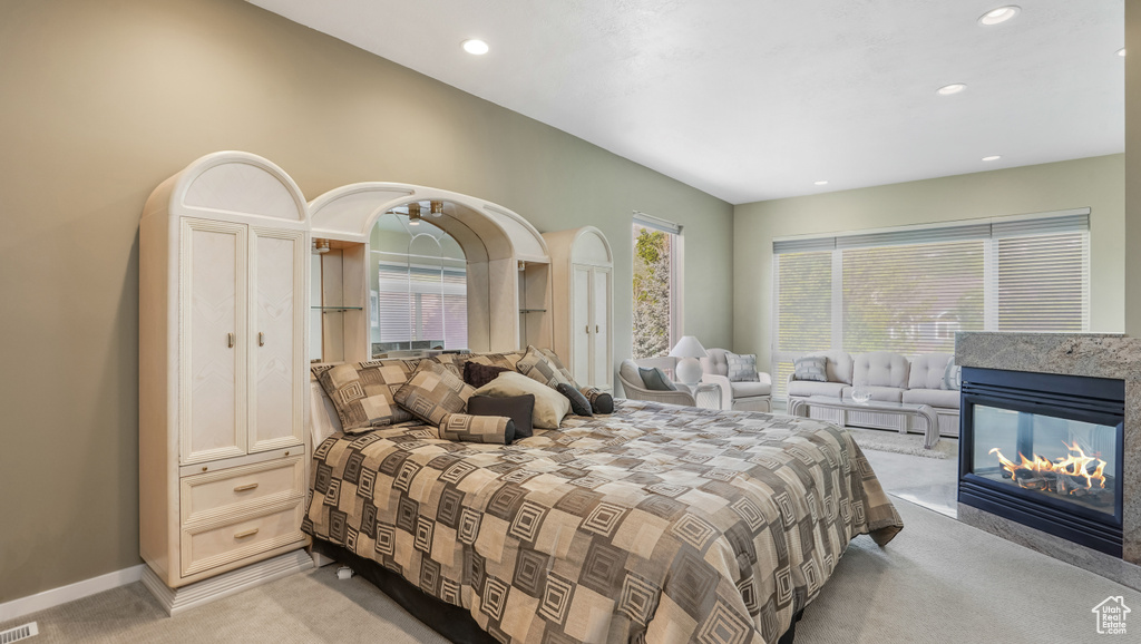 Bedroom with light carpet, recessed lighting, a multi sided fireplace, and baseboards