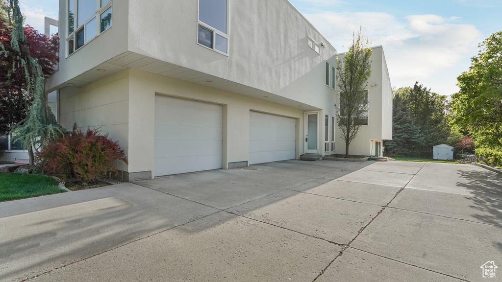 View of property exterior with a garage, stucco siding, and concrete driveway