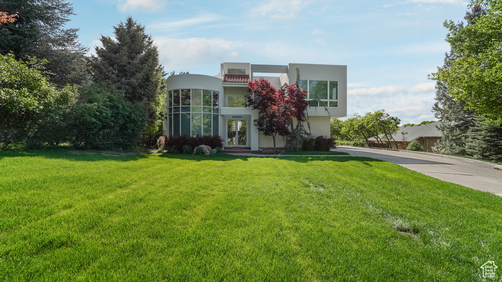 View of front of house featuring stucco siding, french doors, and a front yard