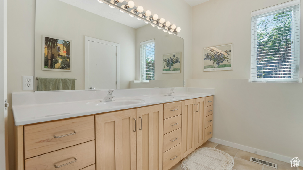 Bathroom with double vanity, tile patterned flooring, and baseboards