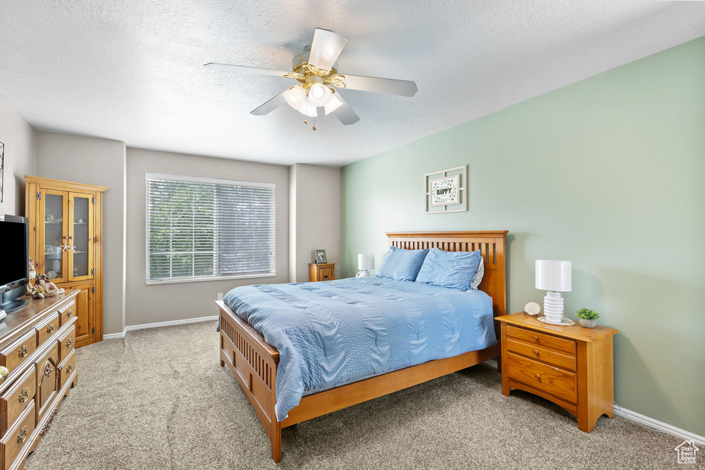 Bedroom featuring light colored carpet, baseboards, a ceiling fan, and a textured ceiling