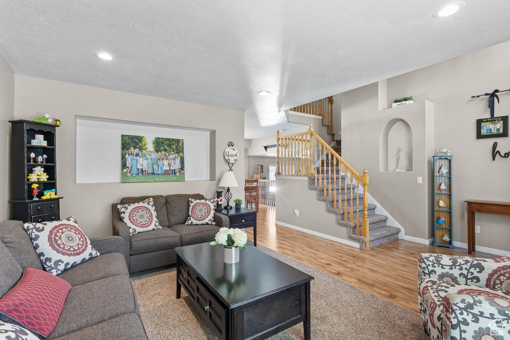 Living area with stairs, recessed lighting, baseboards, wood finished floors, and a textured ceiling