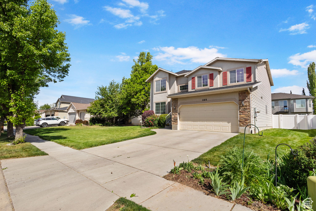 Traditional-style home featuring stone siding, driveway, an attached garage, and stucco siding