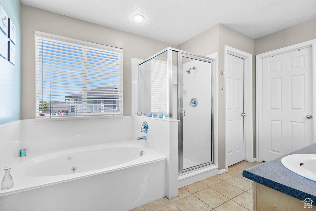 Full bath featuring a garden tub, a stall shower, tile patterned floors, and vanity