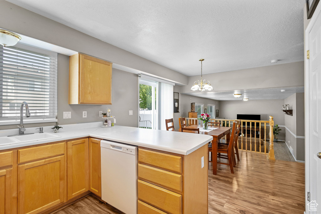 Kitchen with dishwasher, a sink, a peninsula, light wood-style floors, and open floor plan