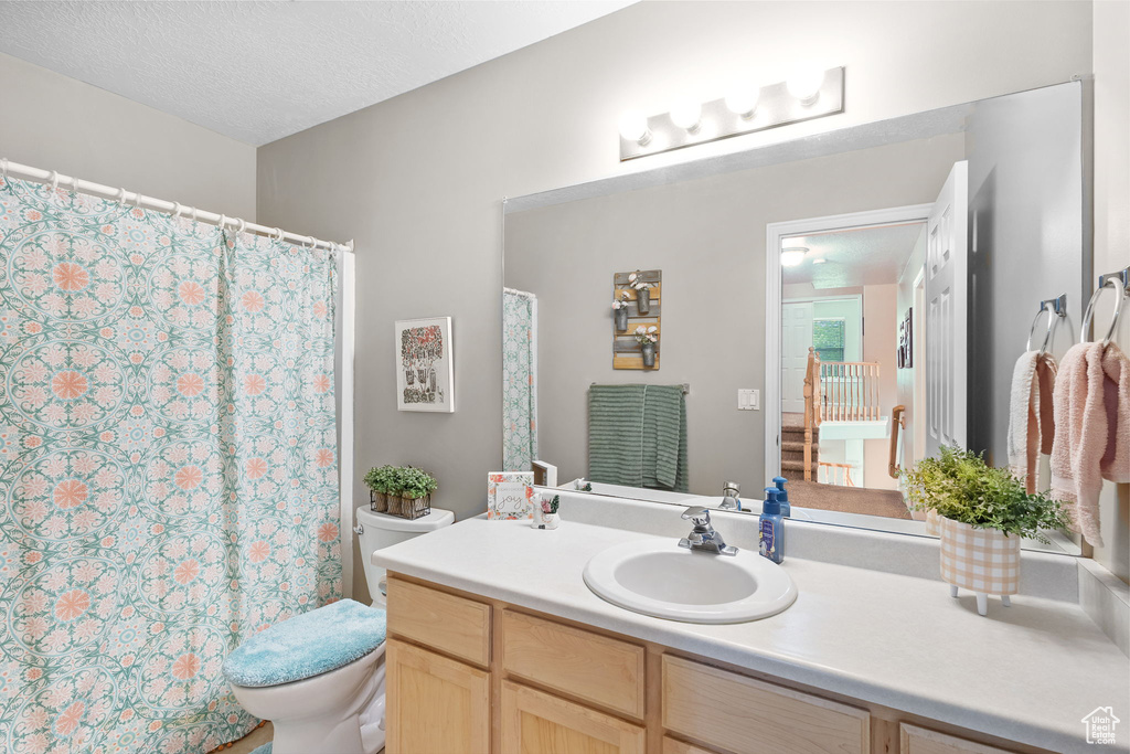 Bathroom featuring toilet, vanity, and a shower with shower curtain