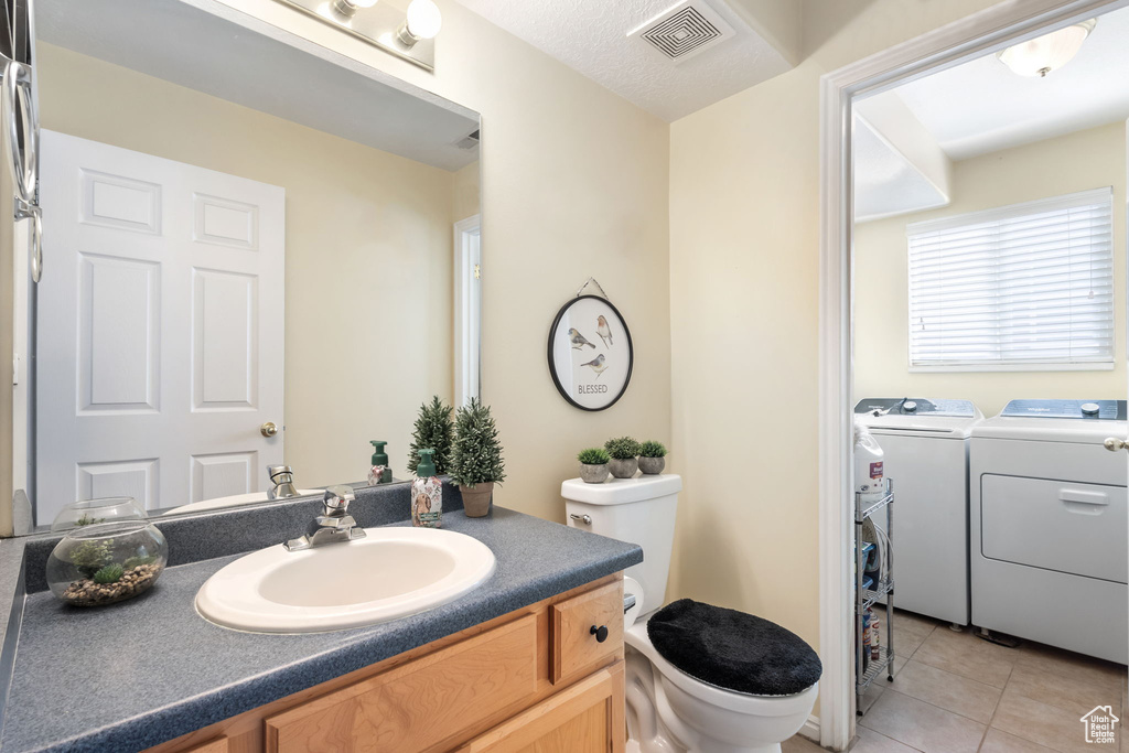 Bathroom with washer and clothes dryer, toilet, tile patterned floors, and vanity