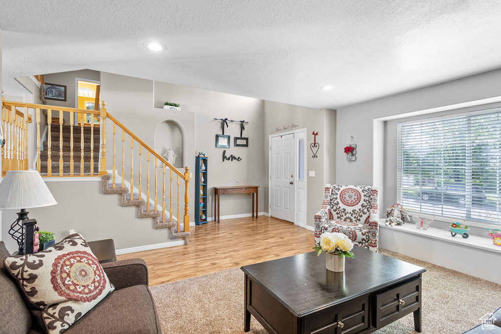Living area with stairway, a textured ceiling, recessed lighting, wood finished floors, and baseboards