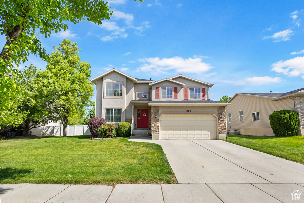 Traditional-style home featuring stone siding, concrete driveway, a garage, and stucco siding