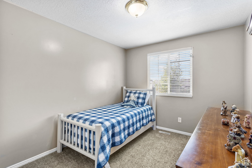 Bedroom featuring carpet flooring, baseboards, and a textured ceiling