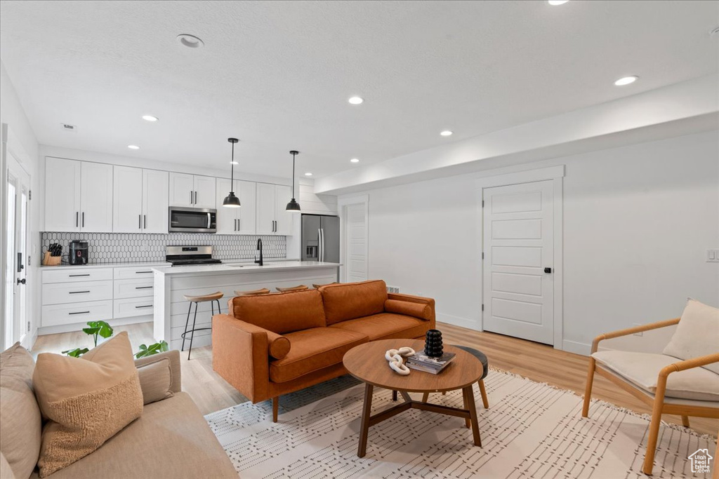 Living room with light wood-type flooring, recessed lighting, and baseboards