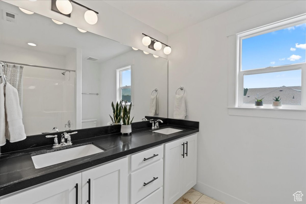 Bathroom with curtained shower, double vanity, and baseboards