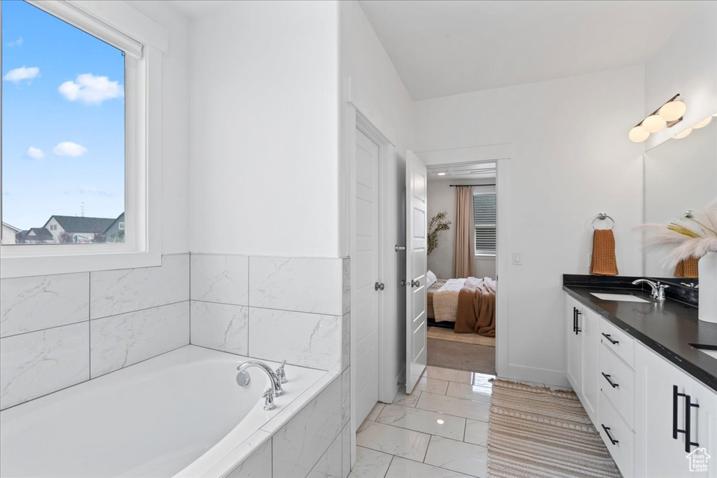 Ensuite bathroom with marble finish flooring, plenty of natural light, double vanity, and a bath
