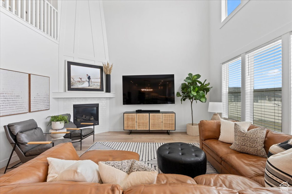 Living area featuring a large fireplace, a high ceiling, plenty of natural light, wood finished floors, and baseboards