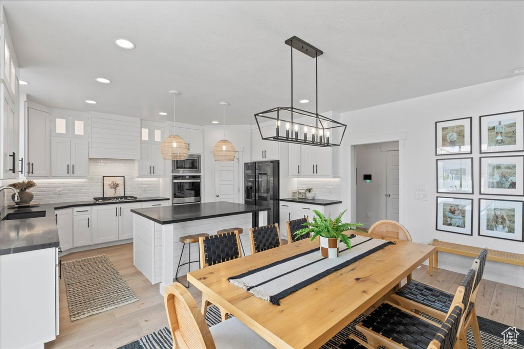 Dining space with light wood finished floors, a chandelier, and recessed lighting
