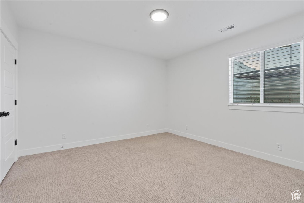 Spare room featuring light colored carpet and baseboards