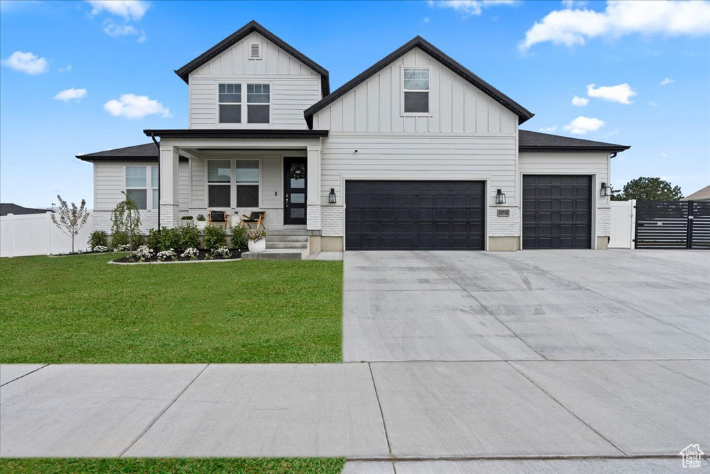 Modern farmhouse featuring board and batten siding, driveway, a porch, and an attached garage