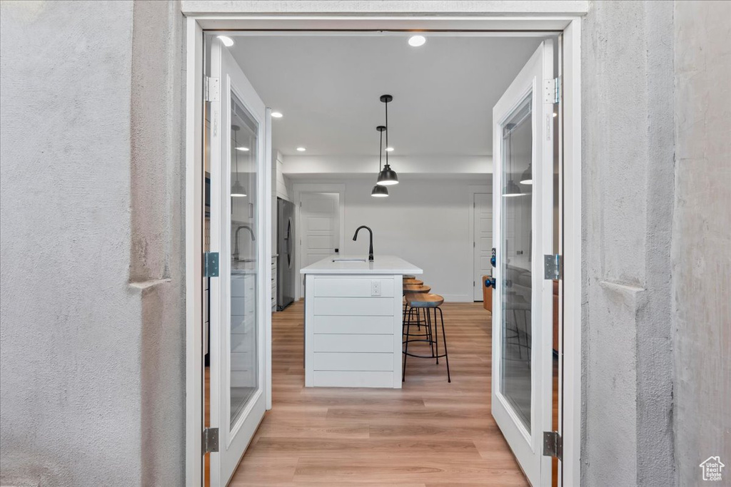 Hallway featuring light wood-style floors, a sink, recessed lighting, and a textured wall