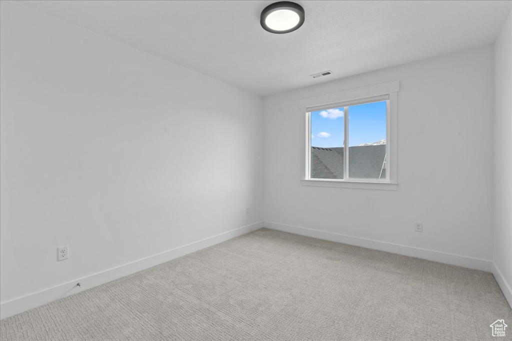 Spare room with baseboards and light colored carpet