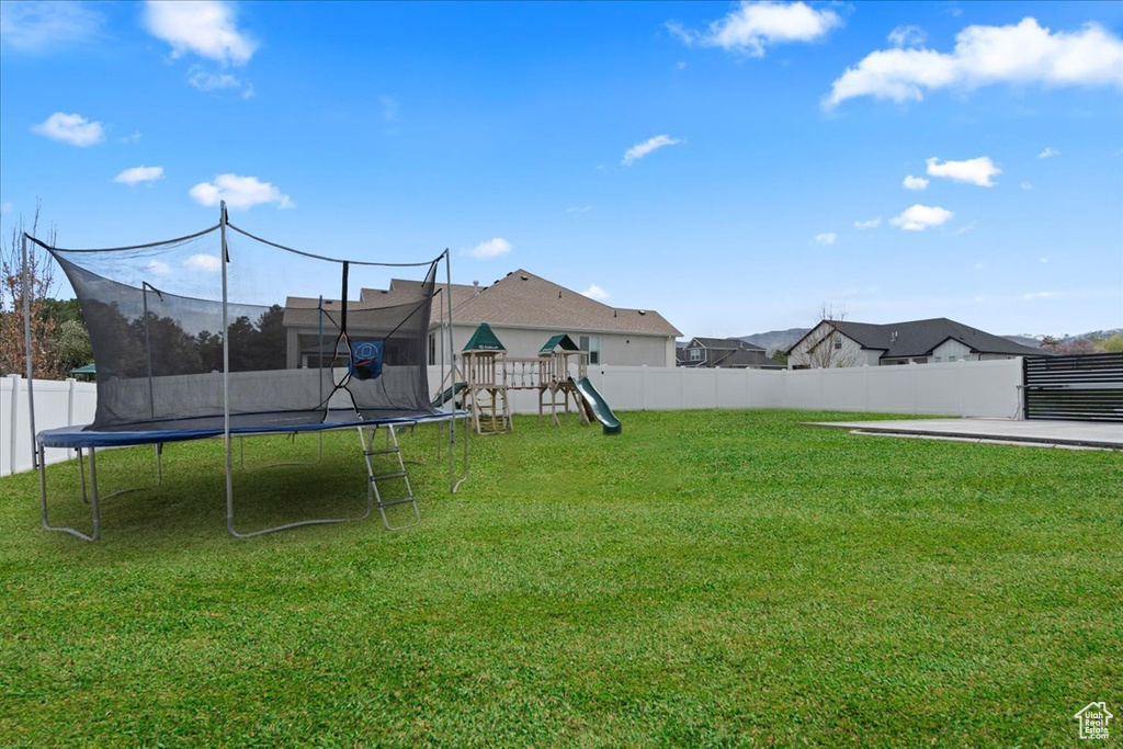 View of yard with a trampoline and a playground