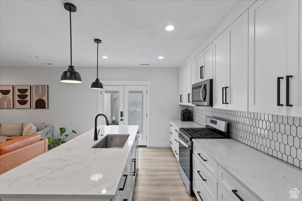 Kitchen featuring stainless steel appliances, a sink, a kitchen island with sink, decorative backsplash, and recessed lighting
