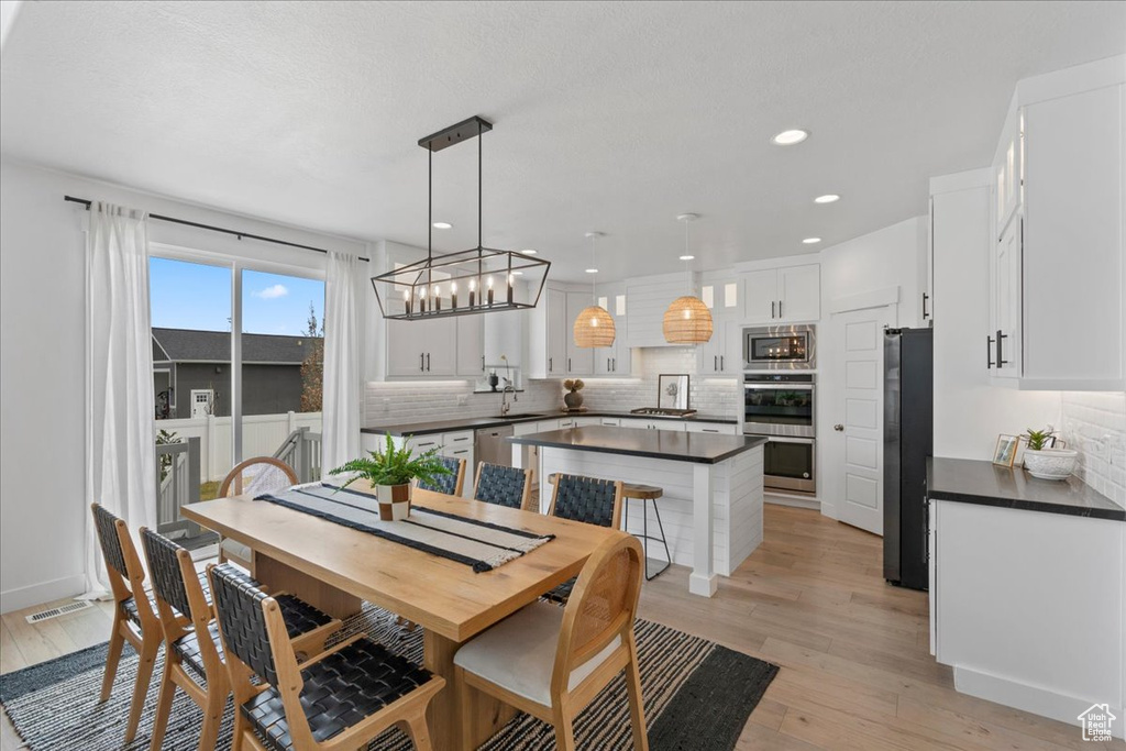 Dining room with light wood-style flooring and recessed lighting