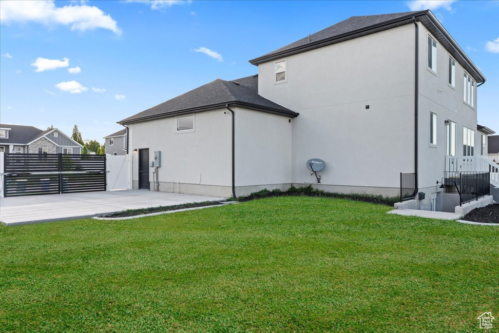Back of house featuring stucco siding, a gate, and a patio