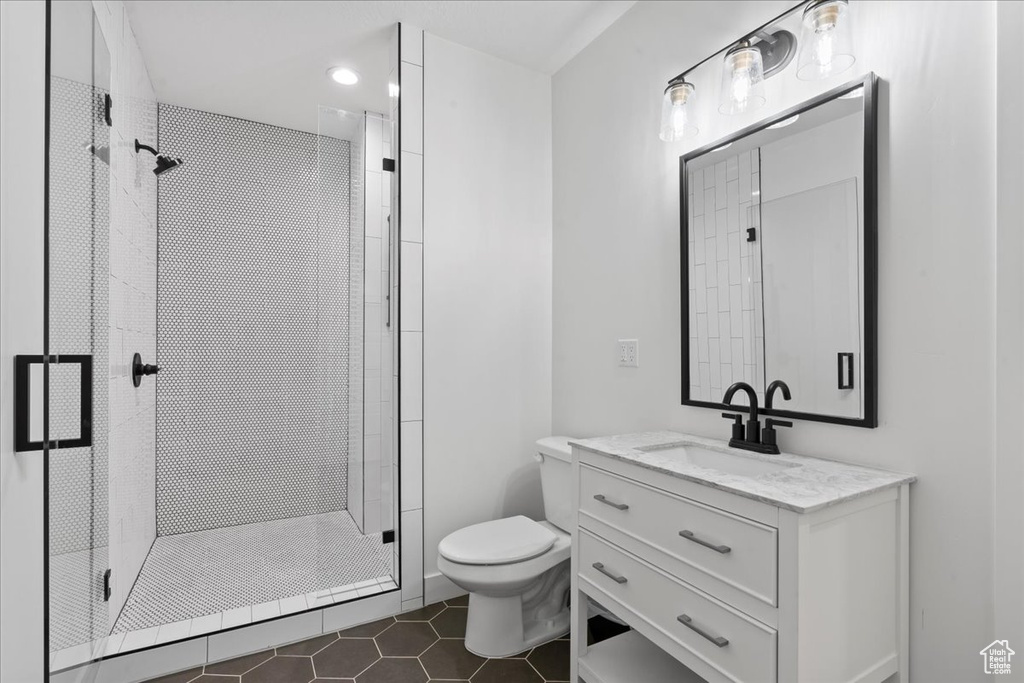 Bathroom featuring toilet, a shower stall, tile patterned floors, and vanity