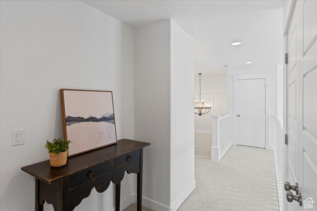 Corridor with light colored carpet, a chandelier, recessed lighting, and baseboards