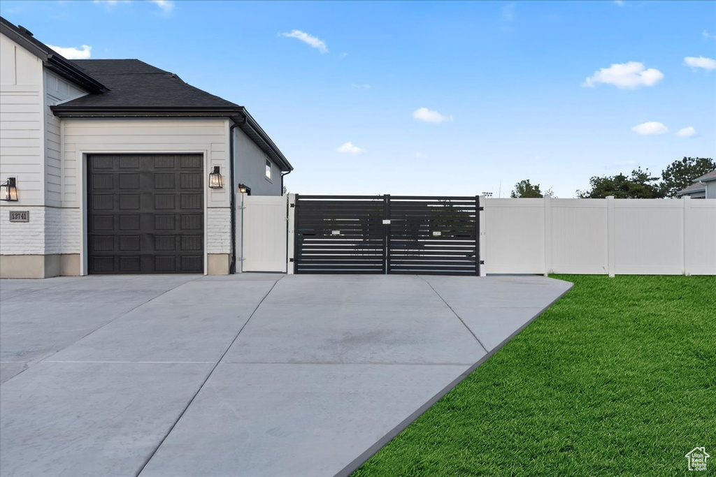 View of side of property with a gate, driveway, and an attached garage