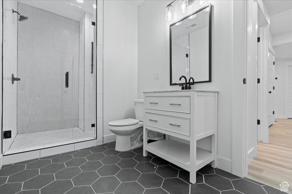 Full bathroom with toilet, a stall shower, tile patterned floors, vanity, and baseboards