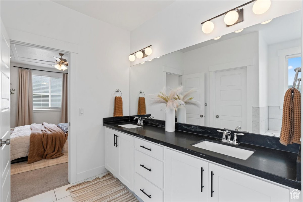 Ensuite bathroom with double vanity, tile patterned floors, ceiling fan, and baseboards