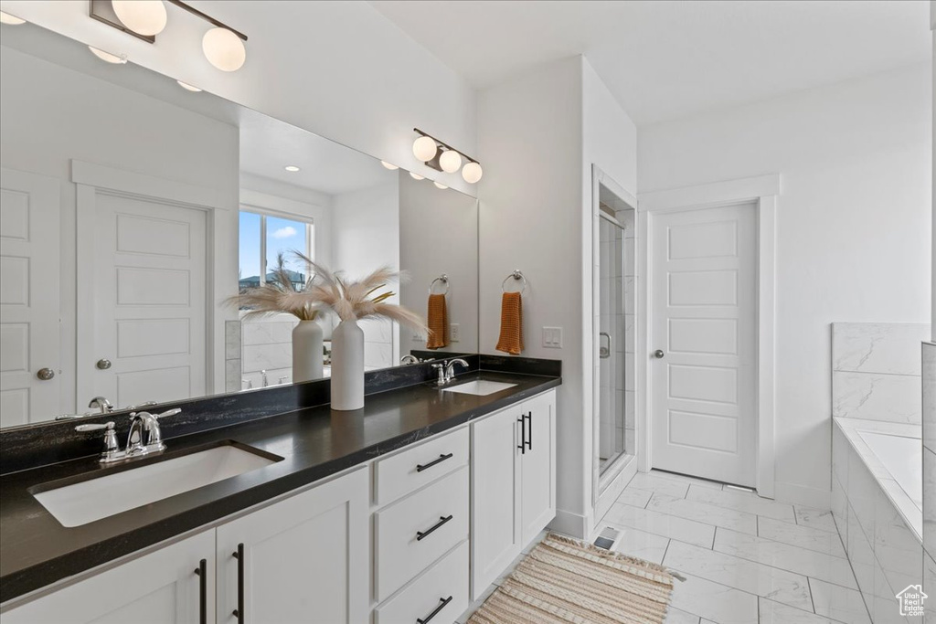 Bathroom with marble finish floors, a shower stall, double vanity, and a tub