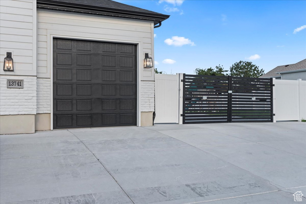 Garage with concrete driveway, fence, and a gate
