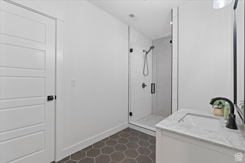 Bathroom with a shower stall, tile patterned floors, baseboards, and vanity