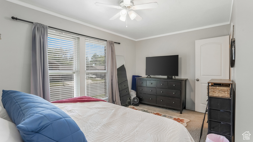 Carpeted bedroom with ornamental molding and ceiling fan
