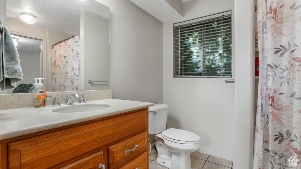 Full bath featuring tile patterned floors, toilet, vanity, and a shower with curtain