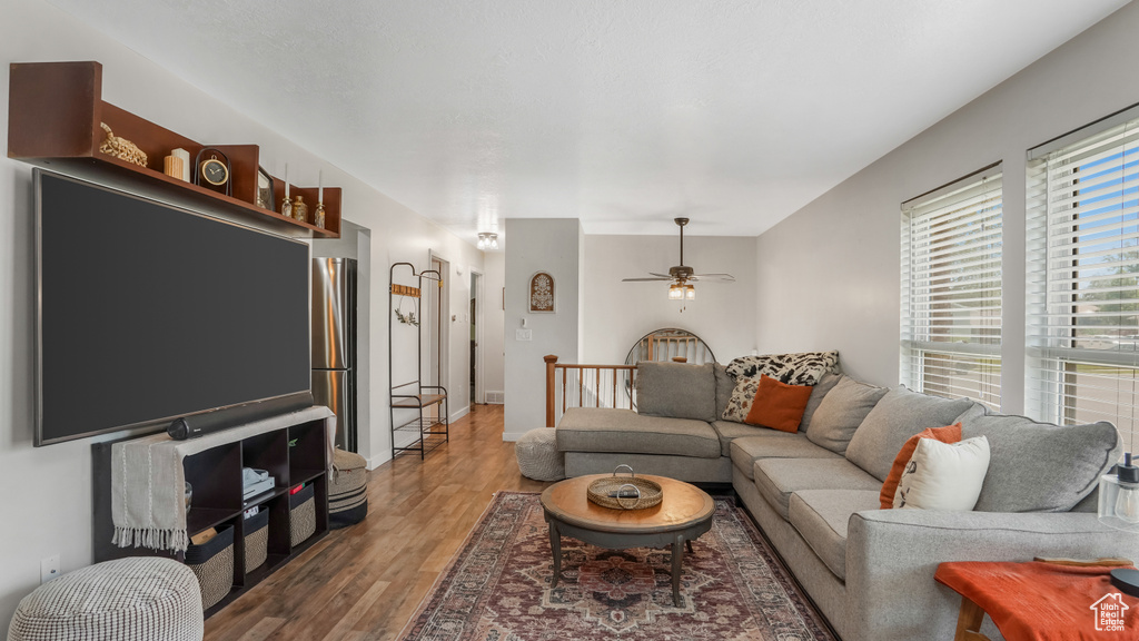 Living area with a ceiling fan, wood finished floors, and baseboards