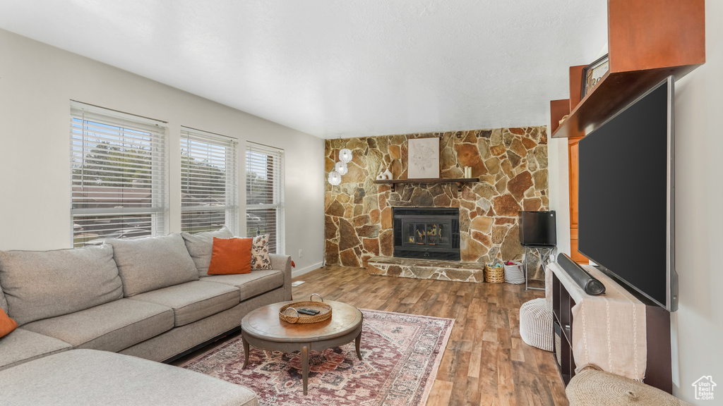 Living area with a stone fireplace, wood finished floors, and baseboards