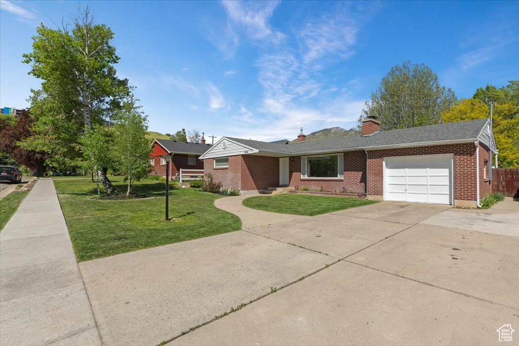 Ranch-style house with brick siding, an attached garage, driveway, and a chimney