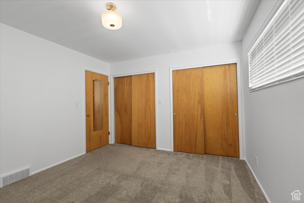 Unfurnished bedroom with multiple closets, carpet, and baseboards