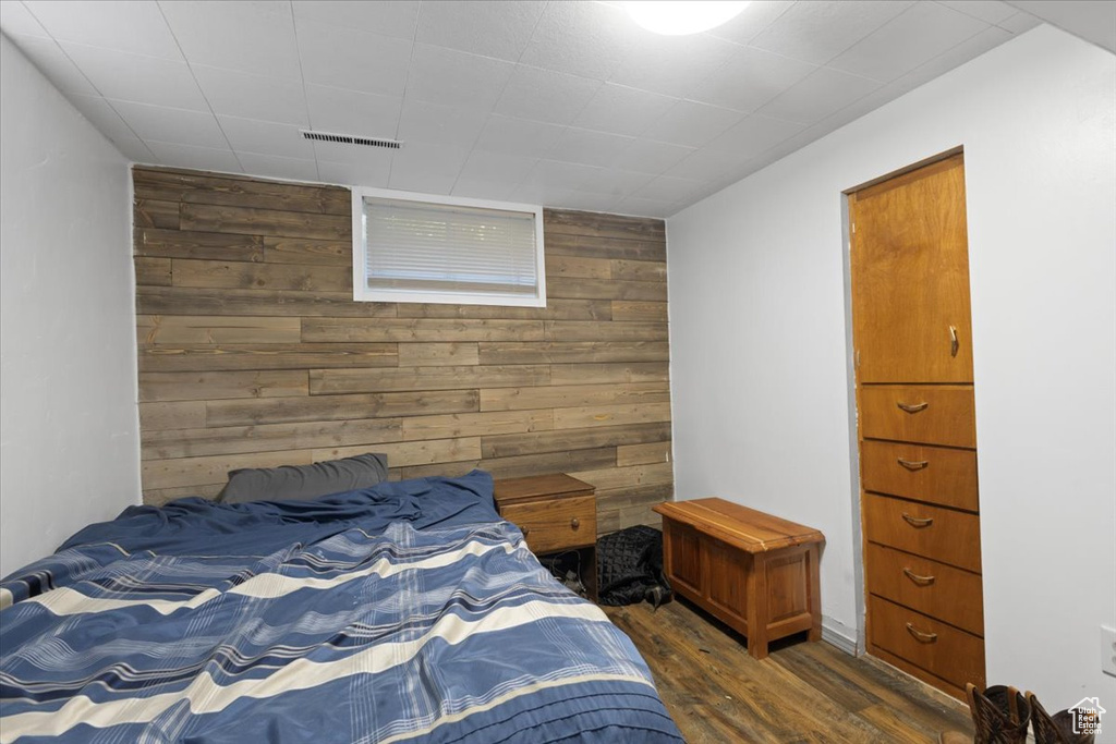 Bedroom featuring wood walls, dark wood-type flooring, and an accent wall