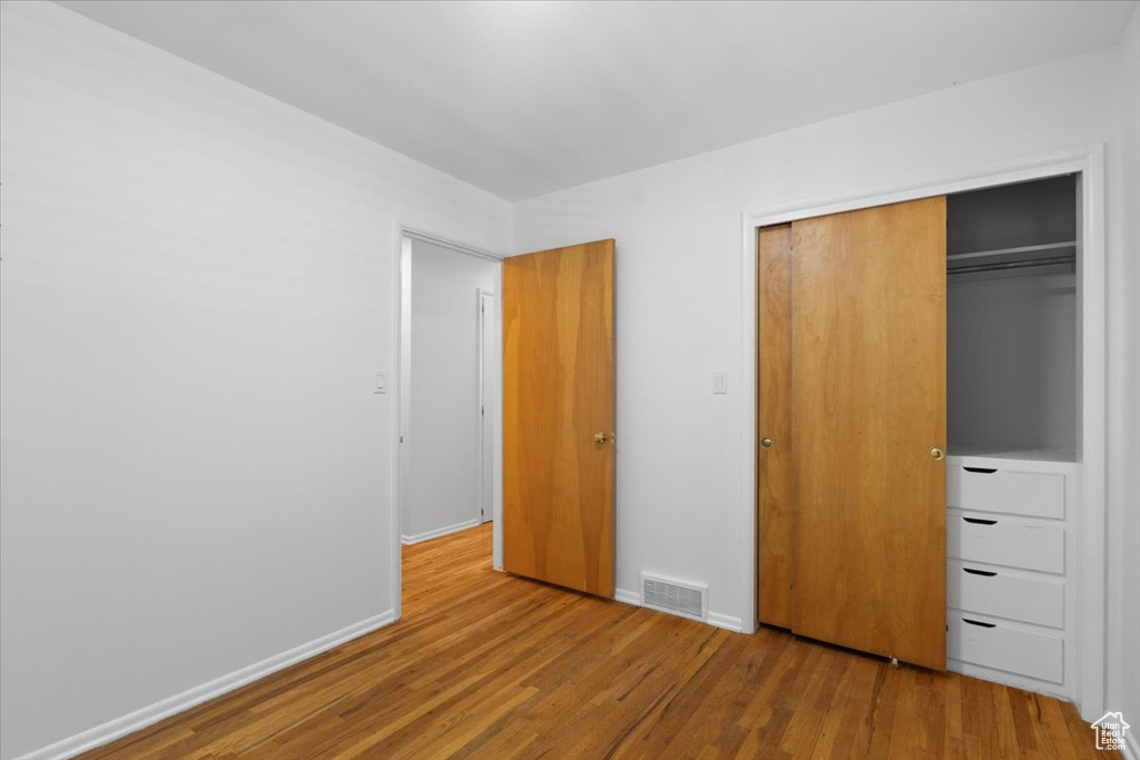 Unfurnished bedroom featuring wood finished floors, a closet, and baseboards