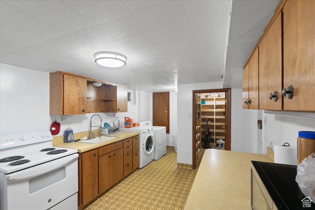 Kitchen with electric stove, washer and dryer, a sink, light countertops, and light flooring