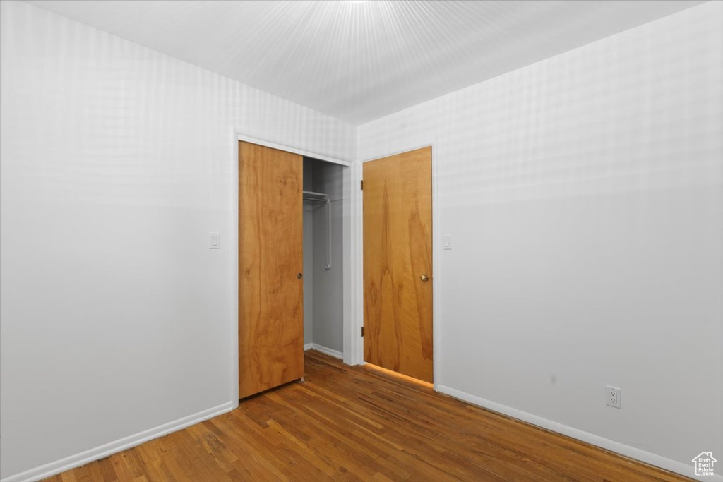 Unfurnished bedroom with wood finished floors, baseboards, and a closet