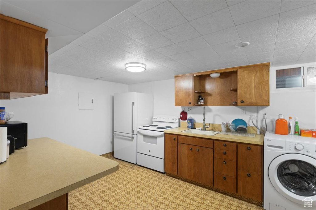 Kitchen featuring washer / dryer, white appliances, brown cabinetry, and light countertops