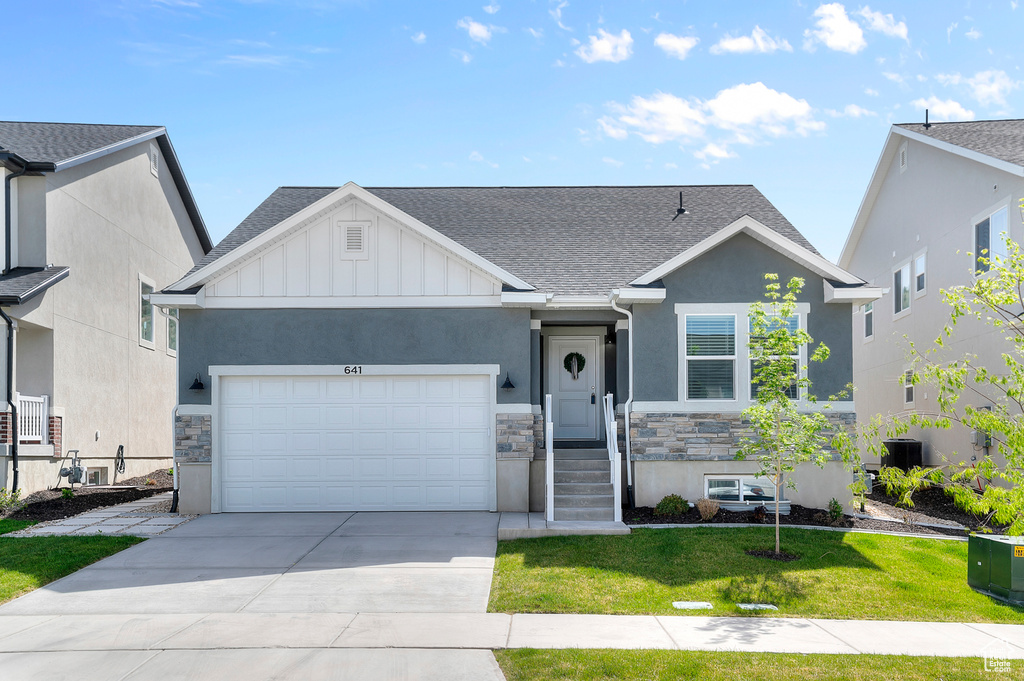 View of front of house featuring stone siding, an attached garage, a shingled roof, and stucco siding