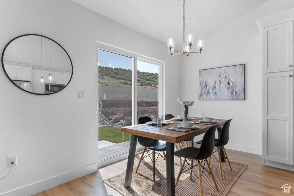 Dining room with baseboards, a chandelier, and light wood finished floors